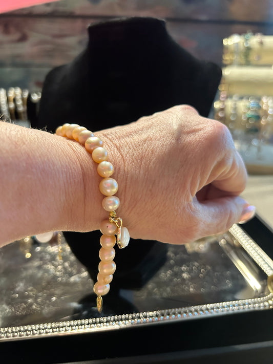 Peach colored freshwater pearl bracelet with shell charm